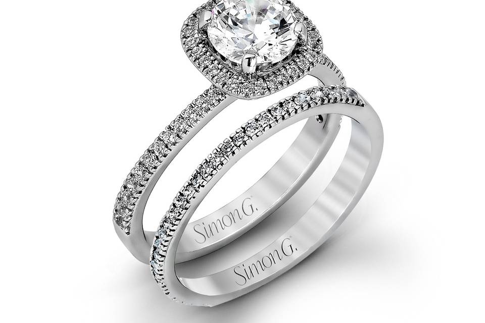 Style MR1842-A <br> Accented by .46 ctw of glistening round cut white diamonds, this contemporary white gold halo style engagement ring and wedding band set makes a dramatic statement.