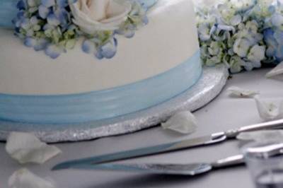 White cake with blue ribbons and flower decor
