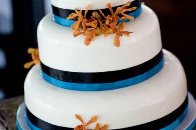 White cake with blue ribbons and flower decor