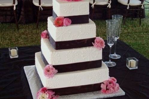 White cake with black ribbon bands and pink flowers