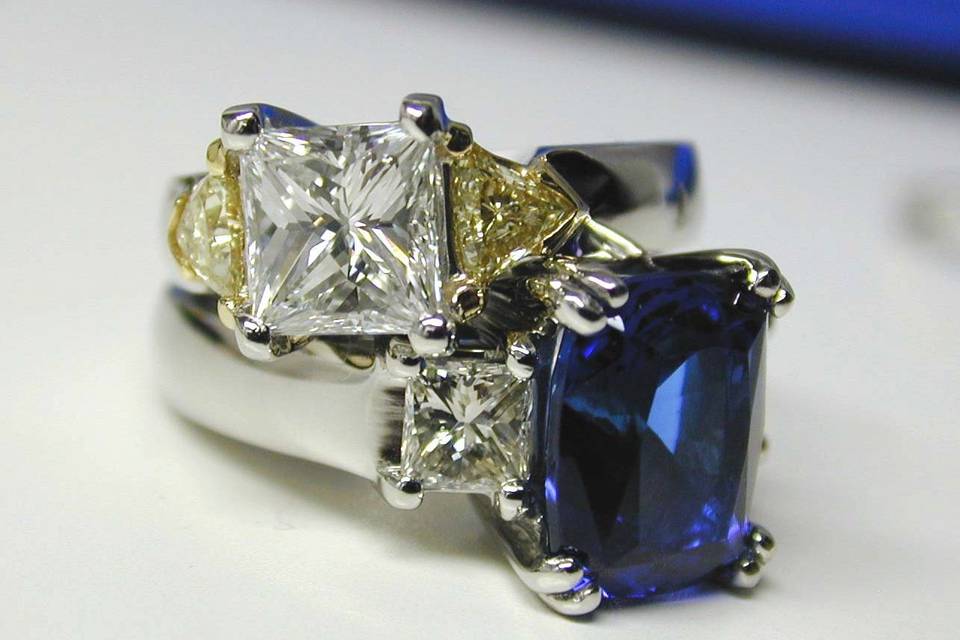 1.55 ct princess cut diamond in heavy hand carved platinum mounting with fancy yellow trillion side stones set in 18kt yellow gold.  6 carat cushion cut Tanzanite set in a heavy, hand carved custom mounting with flanking princess cut diamond side stones.