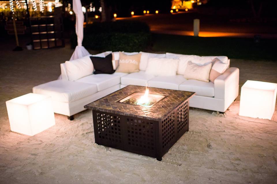 A sleek white sectional with a warm fire pit encourages conversation among your guests.