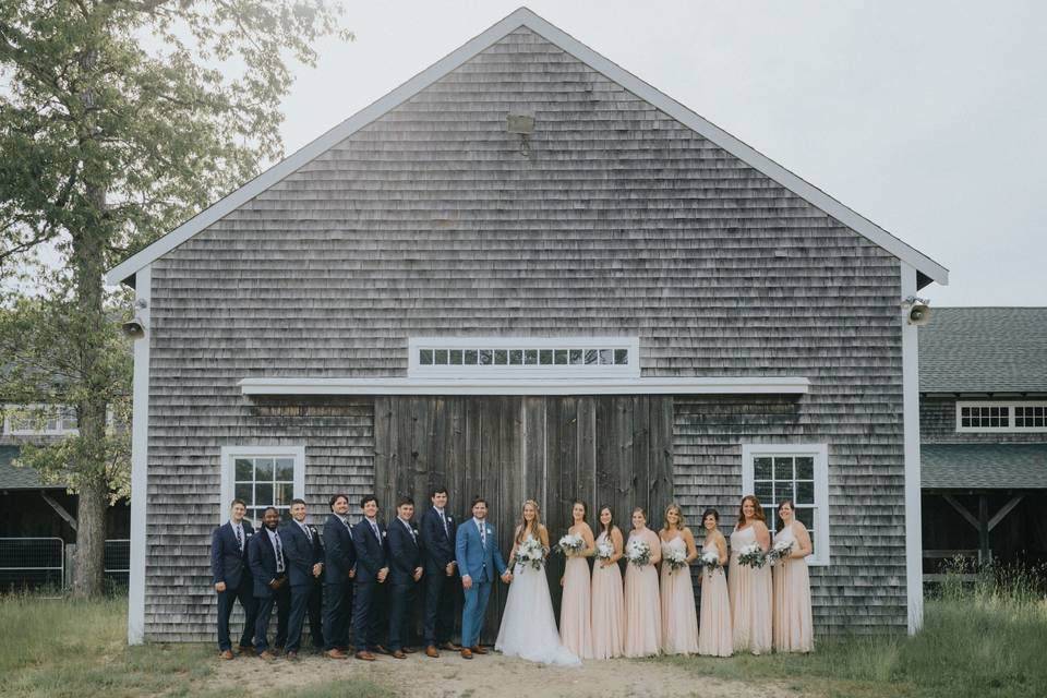 Wedding party posed by barn