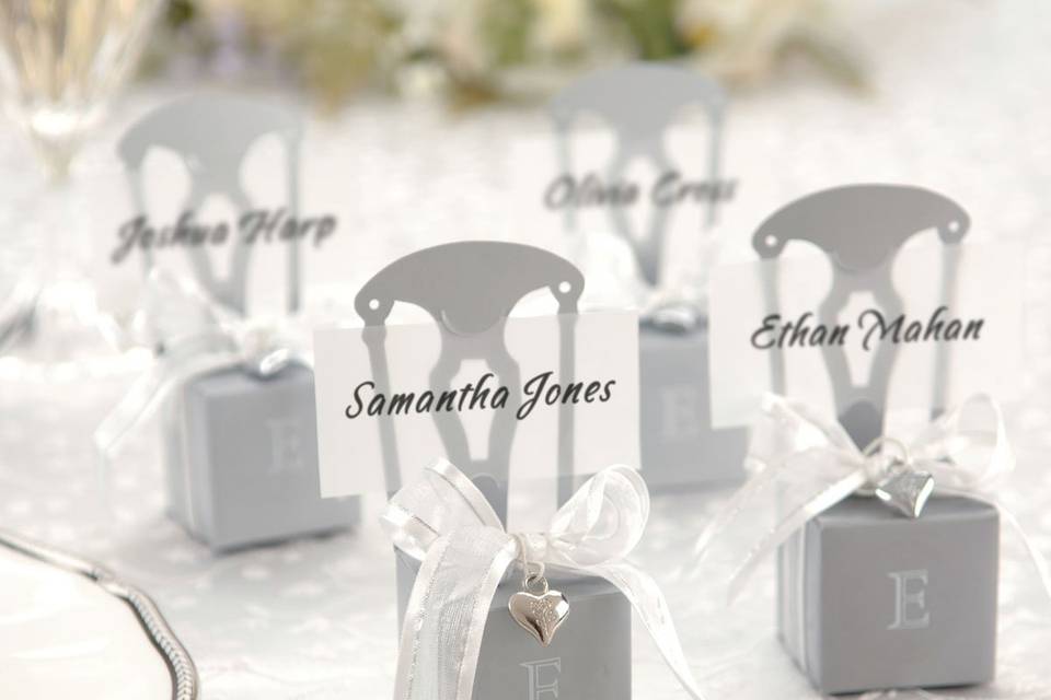 The ideal favor is one that looks beautiful on the table and is still incredibly functional. These miniature silver chairs not only act as place card holders, with their included vellum strip which serves as a place card, but inside the seat of the chair they hold several ounces of whatever special treat you want. Fill them up with flower petals, candies, seeds, potpourri or with chocolate, mints...or anything else you like! Chair comes with an elegant silver and white ribbon and a charming silver heart charm. Measures approximately 4 1/2