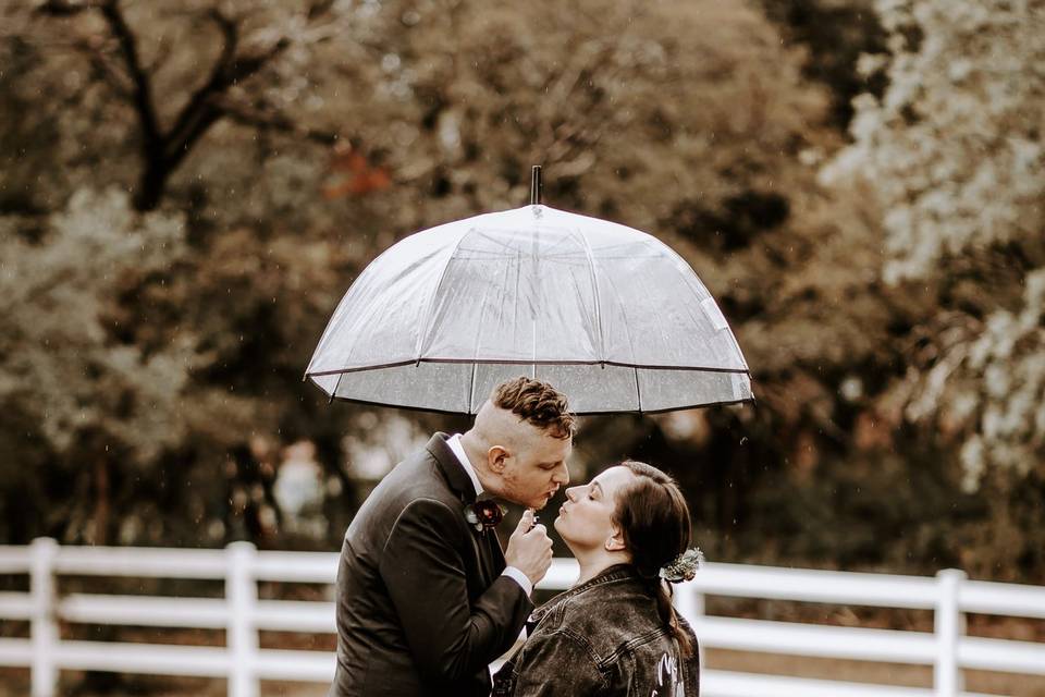 Bride and groom kiss in rain