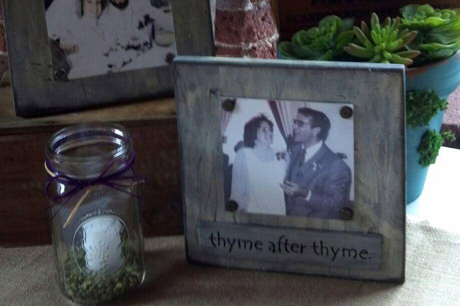 Parent photos on gift table surrounded by wheat and lavender, fresh herb boxes and romantic candles in mason jars. Custom design by Lady Slipper.
