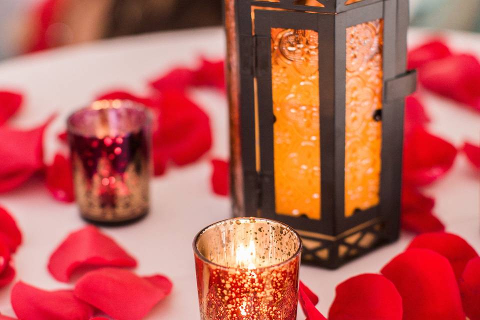 Brilliant colors with petals, lanterns, votives and gold runners.  Photo by Ashley Slater