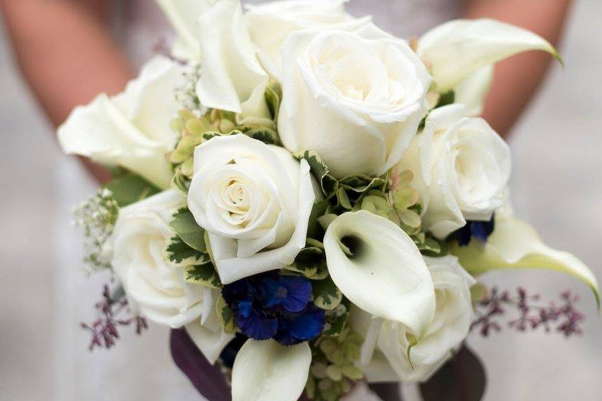 Bridal bouquet of white roses, white mini callas, seeded eucalyptus and touch of navy hydrangea.