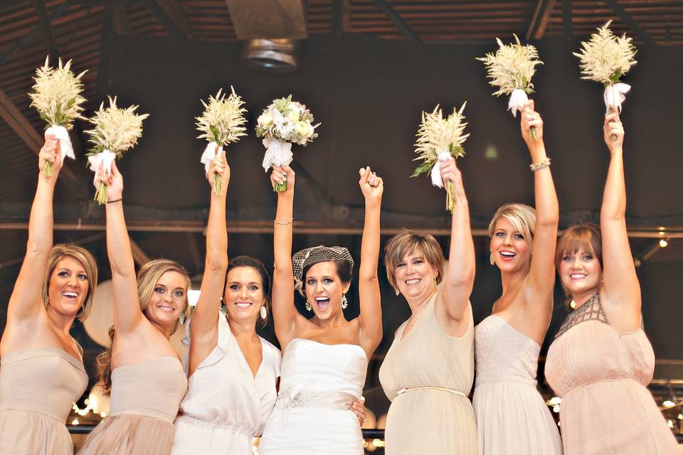 Bride and her bridesmaids and raise their bouquets