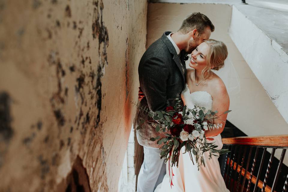 Groom kissing his bride by the stairs