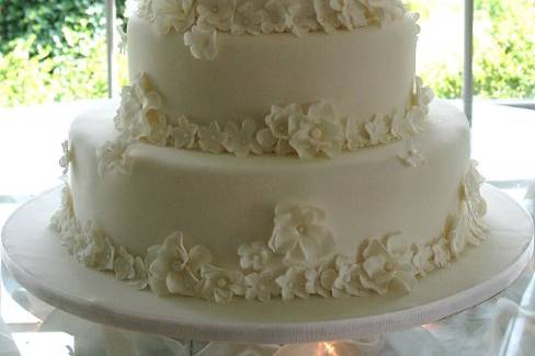 Flower drenched white on white four tier wedding cake. This cake is covered in over 100 handmade sugar flowers