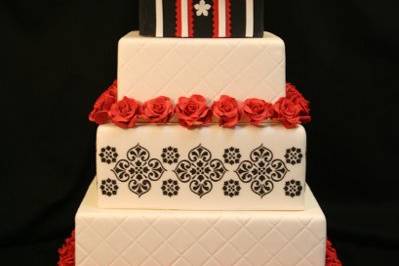 Striking black white and red cake with crisp designs and handmade sugar flowers. Topped with a 