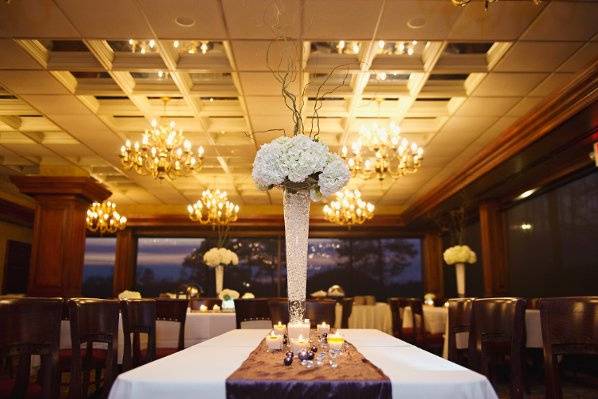 White hydrangea and curly willow arrangements in a pilsner style vase.