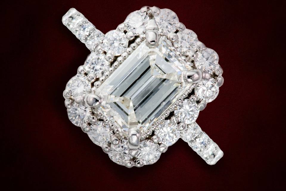 Emerald cut diamond with round brilliant cut diamond accents on this halo engagement ring design