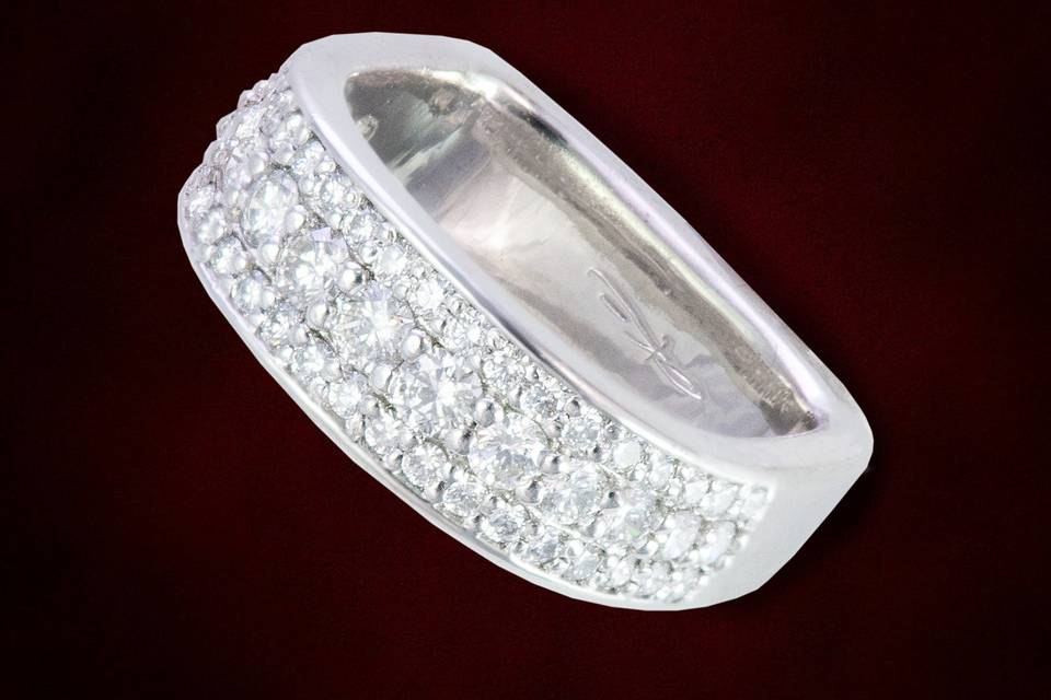 Pave set diamond band with larger diamonds set along the center line and smaller accents on either side.  Designer ring shape prevent the ring from turning when worn and it is tailor fit to your finger.