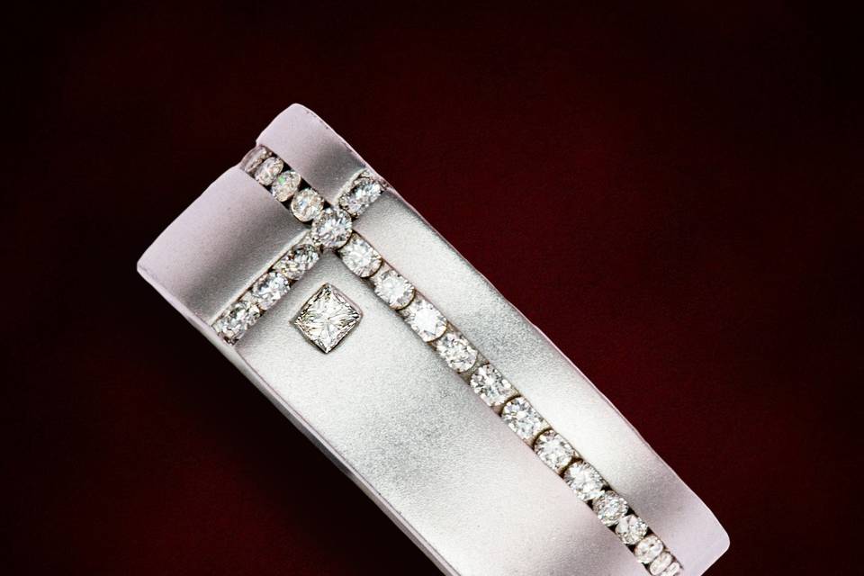 Asymmetrical cross design with square modified and round brilliant cut diamond accents