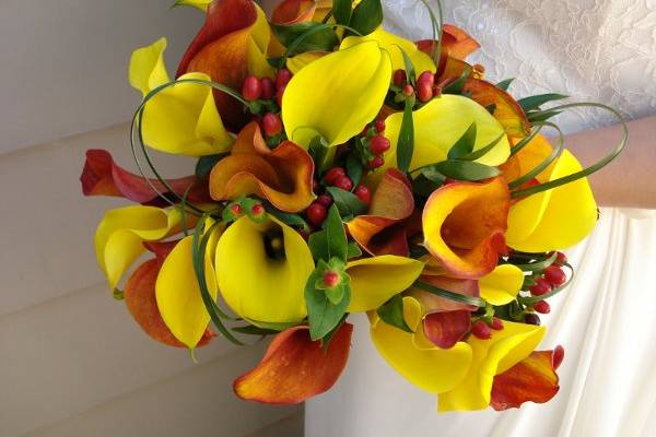 bright yellow and orange calla lilies blend with looped bear grass to create a chic and elegant fall bouquet