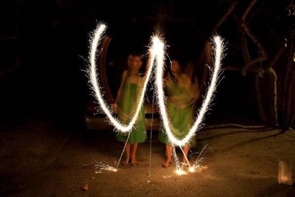 Two bridesmaids creating the married couple's mongram with sparklers.