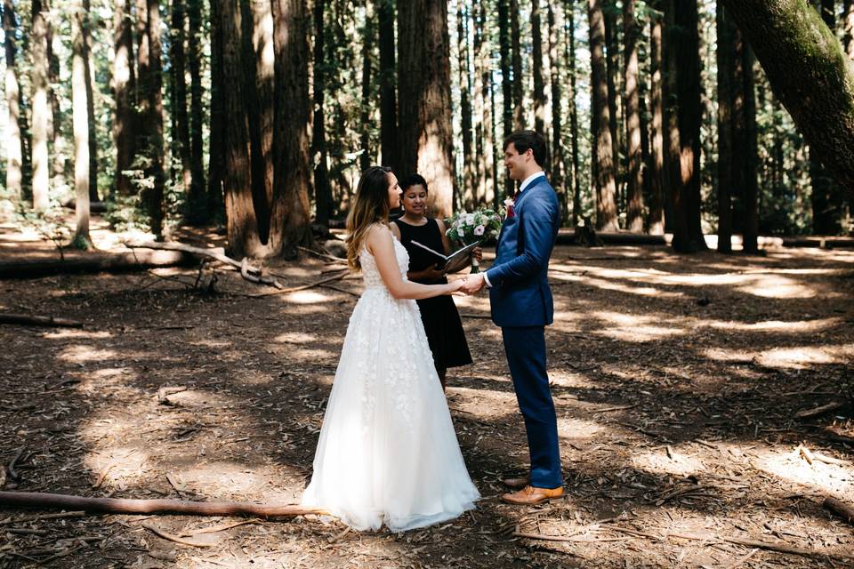 Newlyweds and officiant in the woods