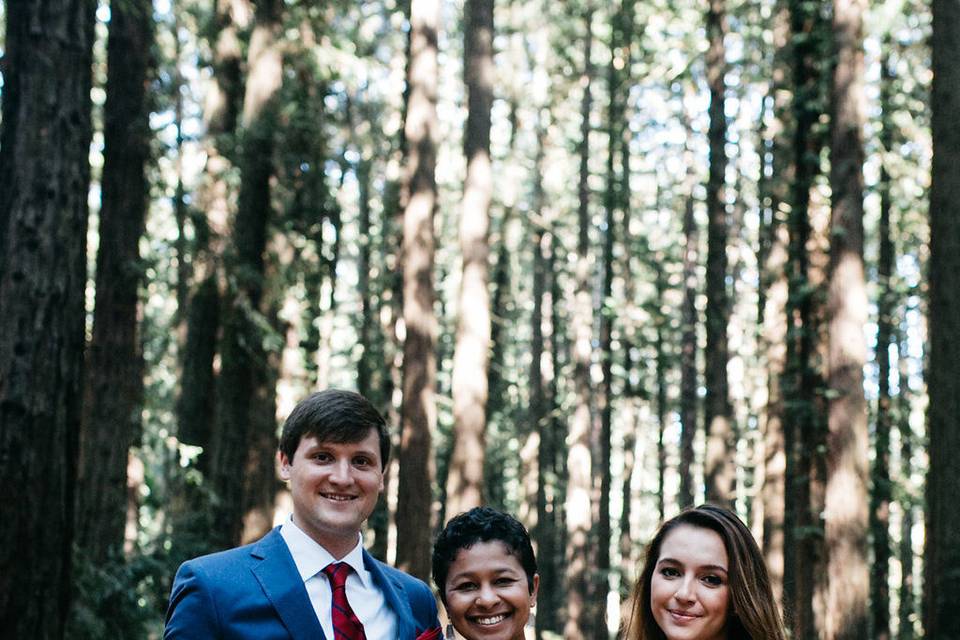 Newlyweds and officiant in the woods