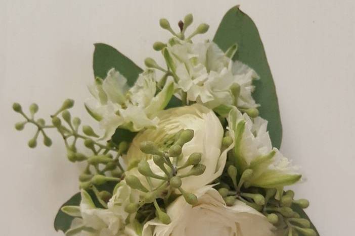 Wrist corsage of white ranunculus, white larkspur and seeded eucalyptus
