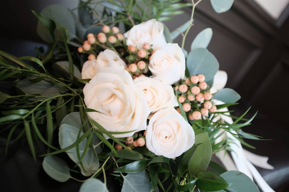 Bride's bouquet of cream roses, peach hypericum berries, silver dollar eucalyptus, and podacarpus.