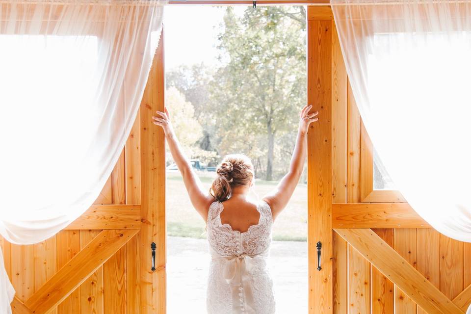 Bride looking out of barn.