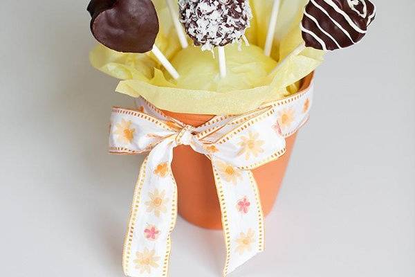 Lollipop Brownies in a Basket
Displayed in a wooden bushel basket surrounded by tissue paper. Each Lollipop Brownie is individually wrapped in a clear plastic bag tied with a metallic twist. Each comes with a card with a photo of the happy couple and a caption of your choice on the front, and our contact information on the back. The baskets are decorated with a beautiful ribbon tied in big bow. The presentation is impressive and can be used as a lovely centerpiece for any table or display.