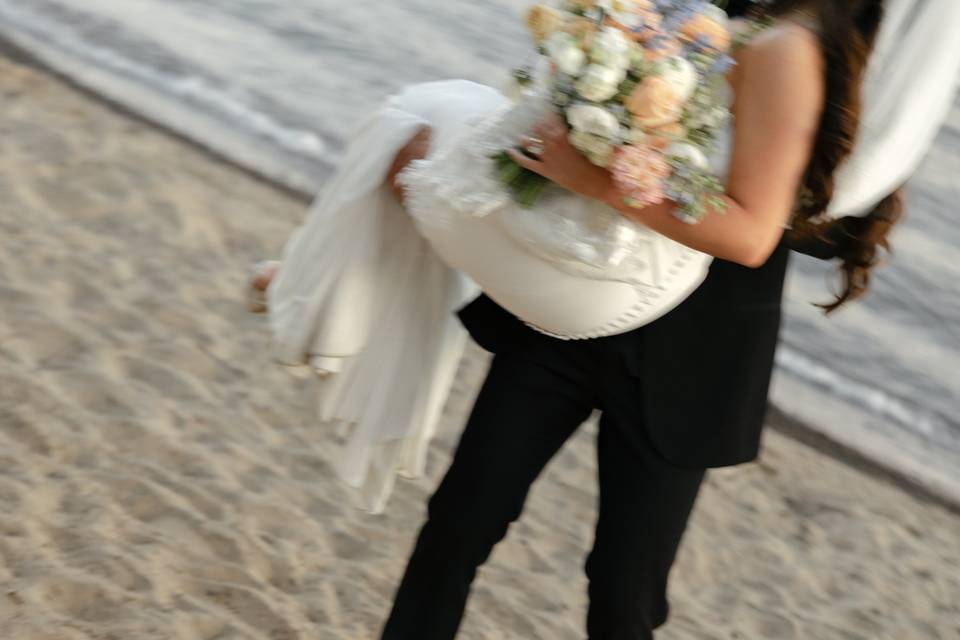 Groom picking up bride beach