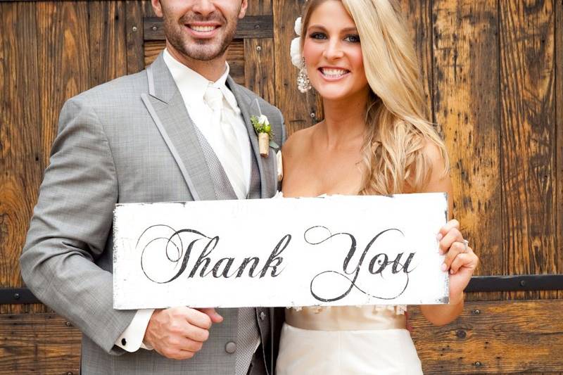 Newlyweds holding up the 'thank you' sign
