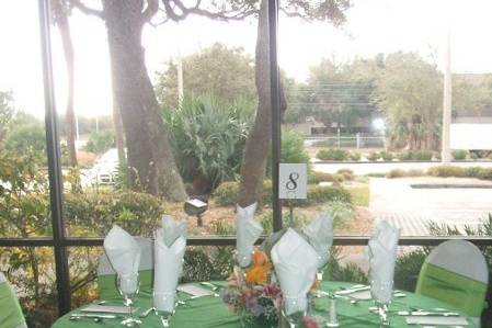 White chair and table covers with light green bows and overlays.