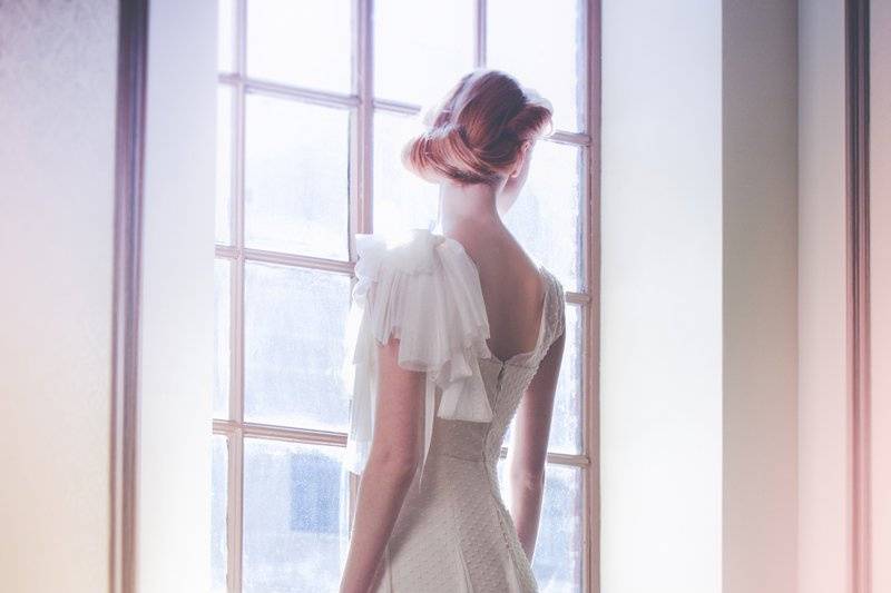 Style: 11004Back- LIERRE Full-length gown in dotted swiss with illusion neckline and cap sleeves. Silk tulle bows at shoulder and scarves throughout skirt. Available in white or ivory. 100% silk.