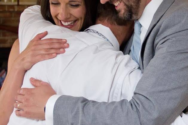 The officiant hugging the newlyweds