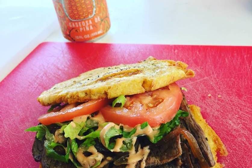 Jibarito, grilled steak, caramelized onions, lettuce, tomatoes and Melecio Sauce between two large tostones