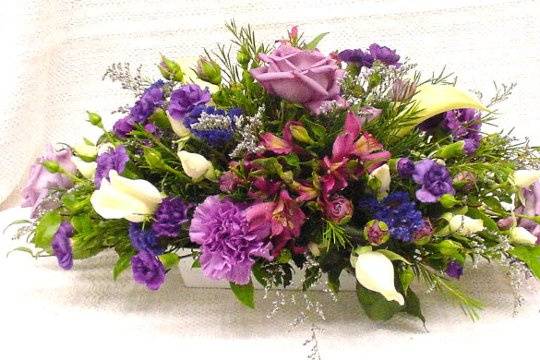 Centerpiece for an oblong table in shades of purple & white.