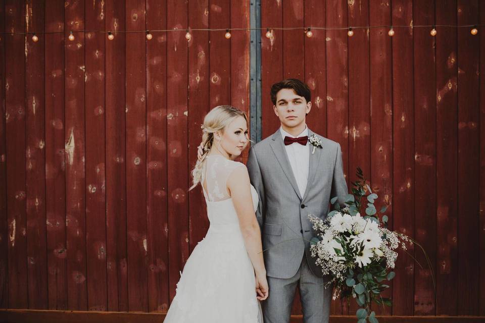 Bride and groom by the barn walls