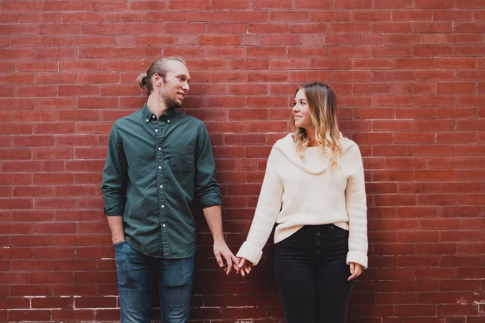 Couple holding hands against brick wall