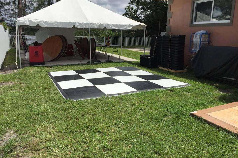 Checkered white and black dance floor. 20'x20' frame Tent in the back.