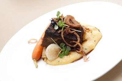 Braised short rib natural demi over creamy chive polenta with baby root vegetables and crispy shallots. Photo credit: Chris Harman