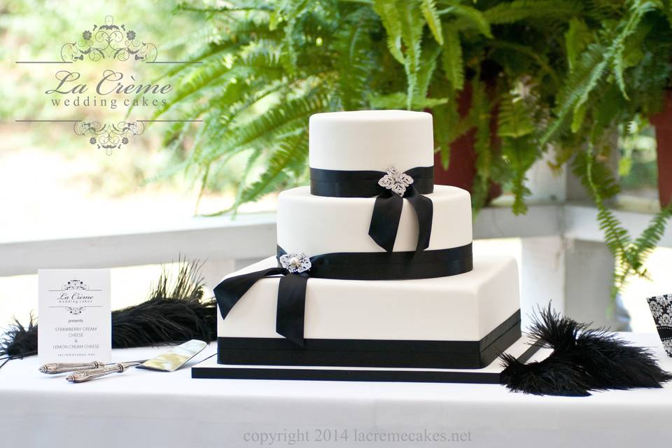 A simple black and white wedding cake adorned with beautiful brooches.