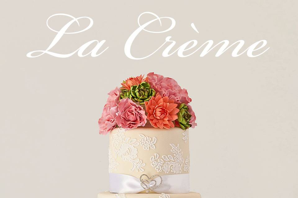 Handmade sugar flowers top this four tier wedding cake covered in pale cream fondant and piped sugar lace. The bride's family brooches add a special personal touch.
