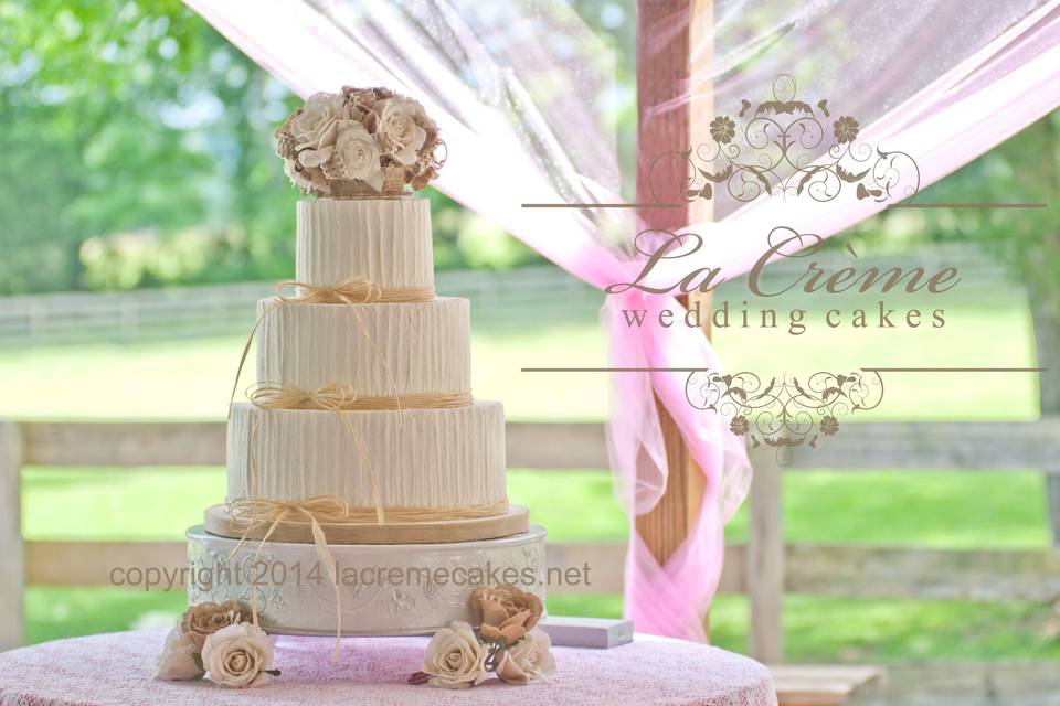 A lovely rustic buttercream wedding cake with raffia ribbon borders and burlap roses