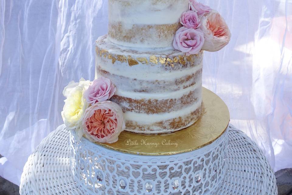 Gorgeous semi naked wedding cake with edible gold leaf and fresh flowers