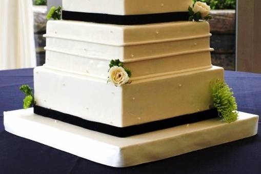 Square, four-tier fondant-covered cake with horizontal lines and pearls.