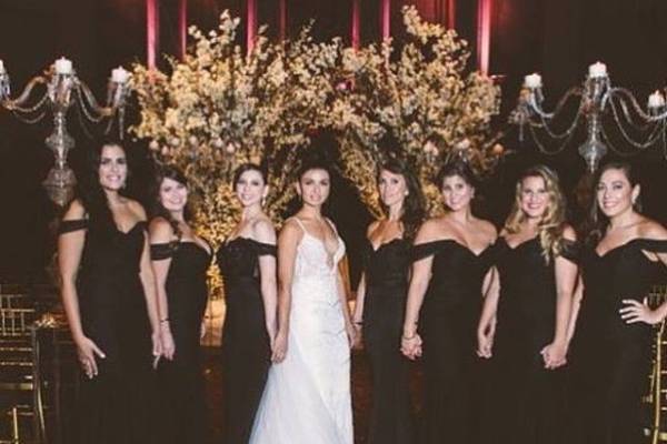 Bridesmaids wearing an off the shoulder dress by Portia and Scarlett in black. Form fitting with a lace train