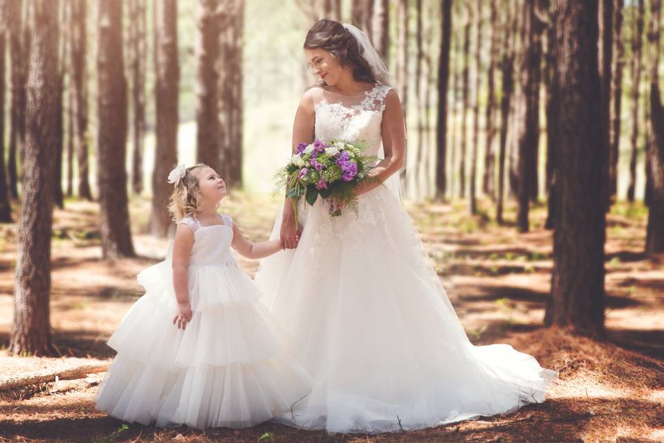 A stunning shot of a bride and flower girl in our pine trees