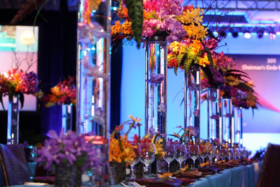 A canopy of orchids held aloft by tall vases and miniature arrangements connected by grasses and orchids for a layered tablescape