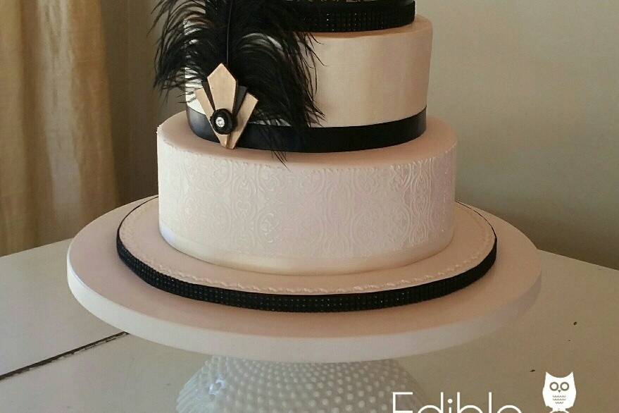 4-tier Art Deco themed wedding cake.  Flower tipped in gold.  6-inch height black focal tier with intricate pattern.  Matching pattern on bottom tier, tone on tone in pearl sheen.