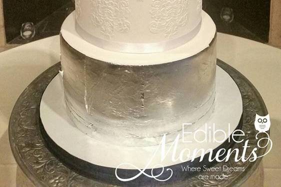 A Classic Beauty to coordinate with the bride's colors of navy & coral.  The top & bottom tier are decored with edible silver leaf.  The focal middle tier is a Double Barrel stenciled with a sophisticated damask pattern.  Wafer paper flowers hand-crafted and custom colored.