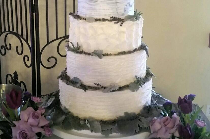 A butter cream beauty accented with edible lace on the top and bottom tiers.  Monogram.  Fresh flower cascade.